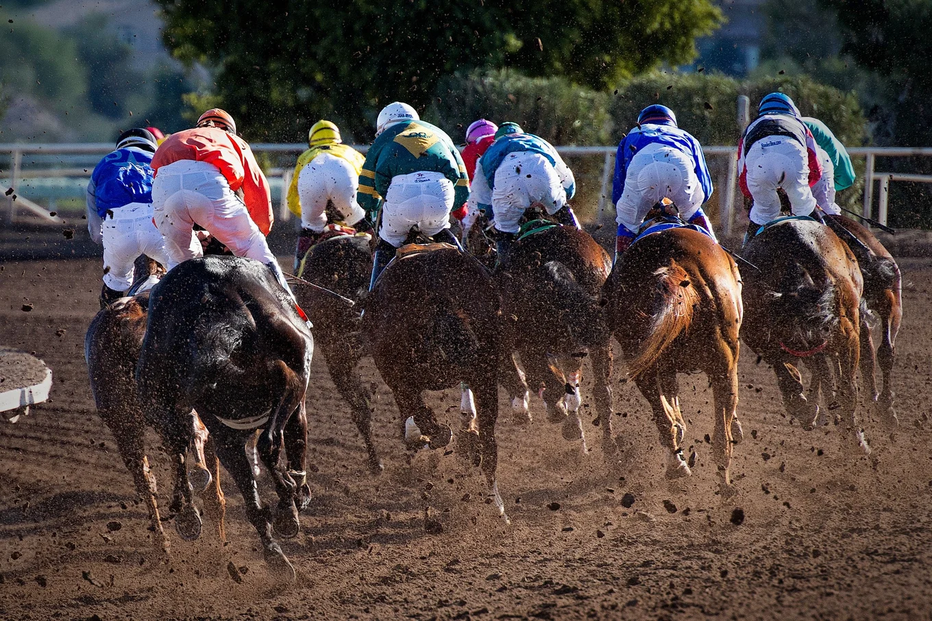 Horses racing with jockeys in colorful attire.
